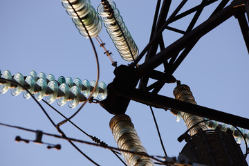 High-voltage towers against the blue sky. High-voltage electrical insulator. Electric hub on pole. Wires of high voltage in sky.