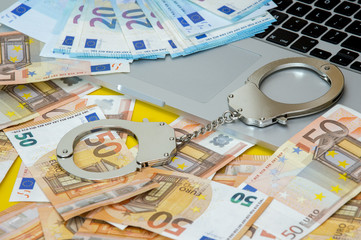 Handcuffs with money on the laptop keyboard.