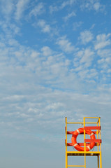 Orange lifeline on yellow lifeguard tower on blue sky background. Vertical.