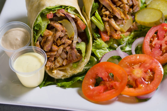 Close shot of a chicken burrito with red tomatoes