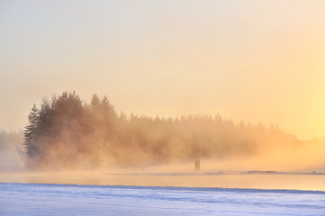 Mist over freezing river on a cold winter day. Winter landscape in Finland.