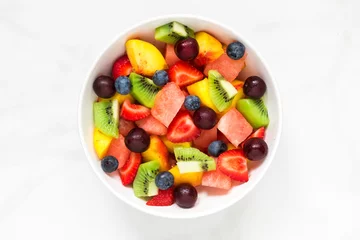 Zelfklevend Fotobehang Vruchten Kom gezonde verse fruitsalade op witte marmeren achtergrond. gezond eten