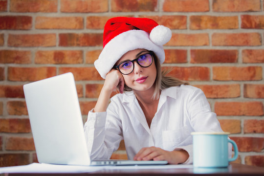 Young Sad Businesswoman In Christmas Hat Sitting At Table With Laptop Computer.