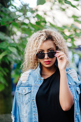 Beautiful African girl in sunglasses with curly hair in city