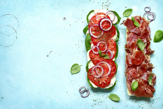 Italian sandwith with prosciutto crudo, mozzarella cheese, salame and basil.Top view with copy space.