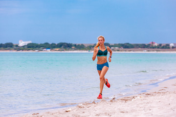 Beautiful sportive woman running along beautiful sandy beach, healthy lifestyle, enjoying active summer vacation near the sea