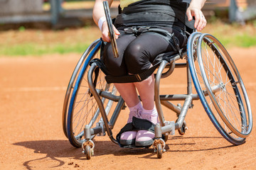 Disabled young woman on wheelchair playing tennis on tennis court.
