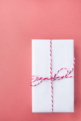 Elegant Gift Box Wrapped in White Paper Tied with Striped Twine on Cherry Pink Background. Christmas New Years Presents Shopping Sale. Elegant Style Mockup