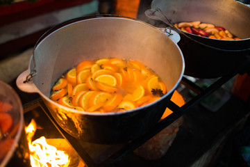 Hot gluhwein or mulled wine in a cauldron at fair, local treat, warm and spicy. A hot wholesome traditional citrus drink on fair. Vitamins in the winter festival. Christmas market.