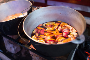 Hot gluhwein or mulled wine in a cauldron at fair, local treat, warm and spicy. A hot wholesome traditional citrus drink on fair. Vitamins in the winter festival. Christmas market.