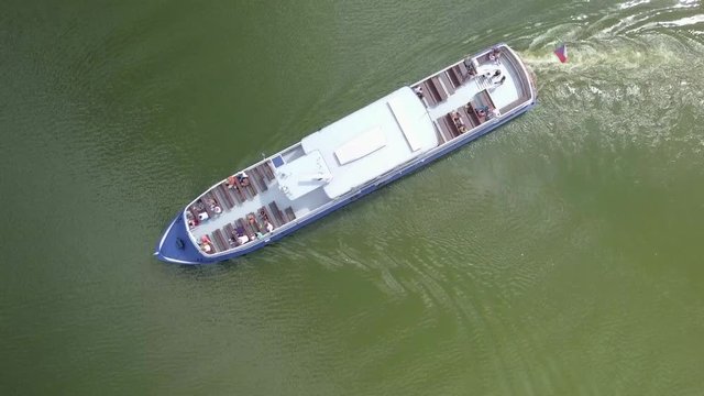 Following a Small tourist cruise boat with people on the upper deck at lake Lipno, South Bohemia - Top down aerial footage