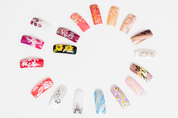 Set of false nails laid out in a spiral on a light background. Isolate materials for manicure. A variety of design nails.