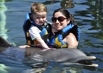 Child and girl with dolphin in blue water. © JUAN CARLOS TINJACA