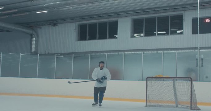 Caucasian male ice hockey player practicing skating drills at the training arena alone. 4K UHD