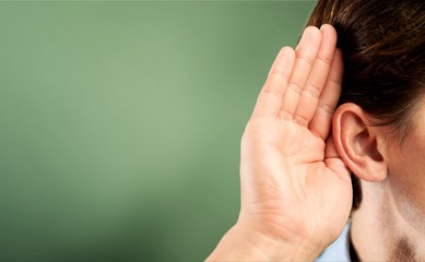 Businessman holds his hand near his ear and listening something