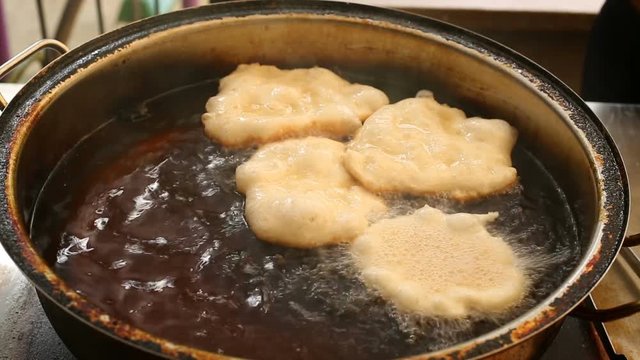 The doughnuts from dough are placed in boiling oil in a pan
