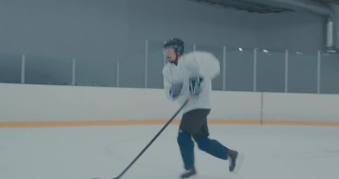 HANDHELD Caucasian Male Ice Hockey Player Practicing Skating Drills At The Training Arena Alone. 4K UHD