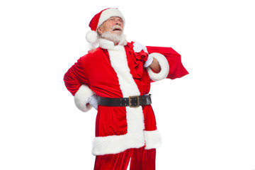 Christmas. Santa Claus is suffering from back pain and holds a red bag with gifts on his back. Isolated on white background.