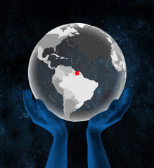 Suriname on translucent globe in hands