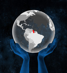 Guyana on translucent globe in hands