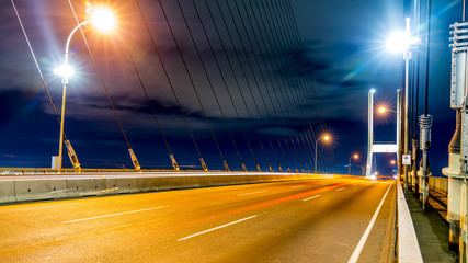 Long exposure at night of Alex Fraser bridge, lights and glitters are seen in the frame. Surrey to...