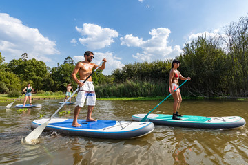 Men and women stand up paddleboarding