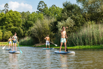 Men and women stand up paddleboarding © homydesign