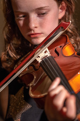 girl playing violin looking at bow