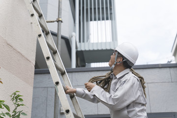 工事現場イメージ・建物を調査するビジネスマン　はしごを登る