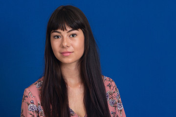 Portrait of a young beautiful woman with long hair in a studio on a blue backdrop