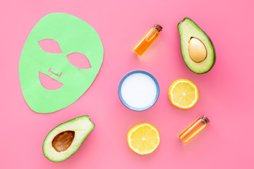 Skin care. Facial mask, cream and lotion near avocado and lemon on pink background top view