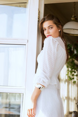 Beautiful girl in white dress stands in the doorway. Emotional portrait, film effect, author's processing.