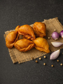 Packshot close up view of "Pan Klib" traditional mini Thai puff dessert stuffed material with fish, curry, shallot, pepper seasoned sugar and salt on sackcloth and black rough back ground