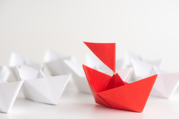 Leadership concept. red paper ship lead among white. One leader ship leads other ships.