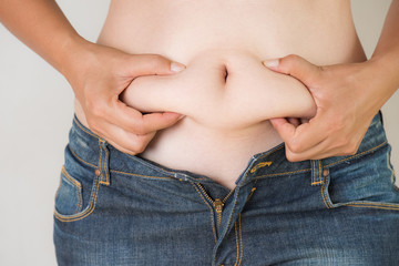 Naklejka premium Fat woman hand holding her own belly fat. woman diet lifestyle to reduce belly and shape up healthy stomach muscle concept.