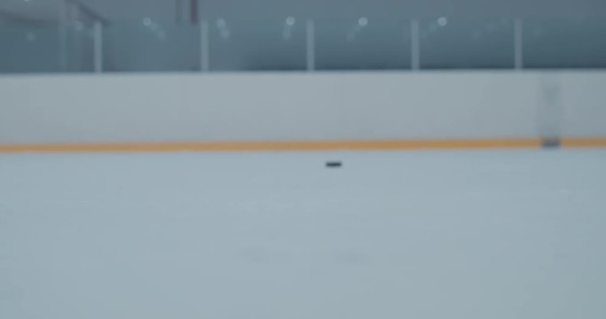 CU ice hockey player shooting a puck at the training arena. 4K UHD