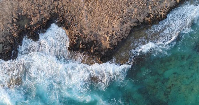 Aerial view of coast line. Top view footage of waves and shore. Cyprus shore at sunset time. Beauterful small bay near Ayia Napa.