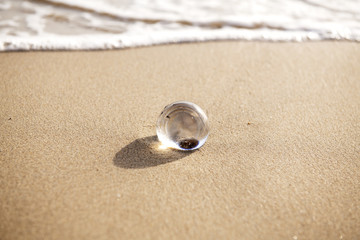 Fototapeta na wymiar glass ball crystal clear reflecting the sea and beach in the morning