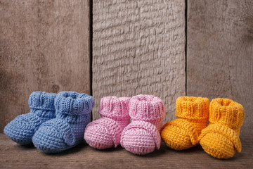 baby concept: different colored baby booties, Three pairs of baby booties on a wooden background