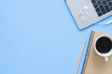 Minimal work space - Creative flat lay photo of workspace desk. Top view office desk with laptop, notebooks and coffee cup on blue color background. Top view with copy space, flat lay photography.