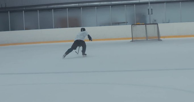 HANDHELD Caucasian male ice hockey player practicing skating drills at the training arena alone. 4K UHD