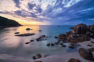 Dramatic colourful sunrise over the sea rocky bay with sail boat
