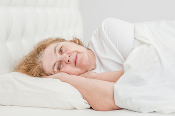 Happy senior woman lying on the bed