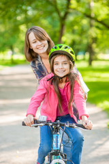 Fototapeta na wymiar mom teaches her daughter to ride a bicycle in the park