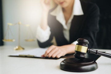 Business woman or lawyers discussing contract papers with brass scale on wooden desk in office. Law, legal services, advice, Justice and real estate concept.