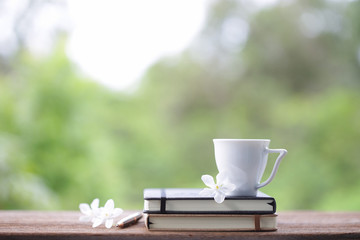 White cup with frangipani flower and notebooks