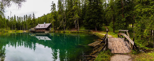 Wonderful emerald-colored lake with wooden bridge and cabin near Cortina d'Ampezzo in the Dolomites, Italy