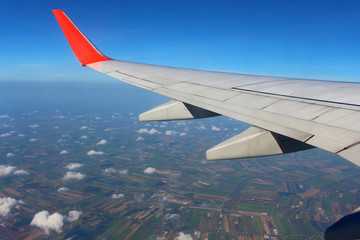 Wing of an airplane flying above the cloud looks from the window of the plane