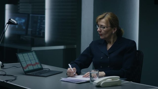 Female Interrogation Expert Conducts Lie Detector / Polygraph Test on a Suspect, She Writes Down Reactions. Computer Measures Physiological indices.