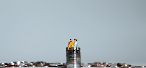 The notion of preparing for the expense of one's old age. A pile of coins and miniature people.